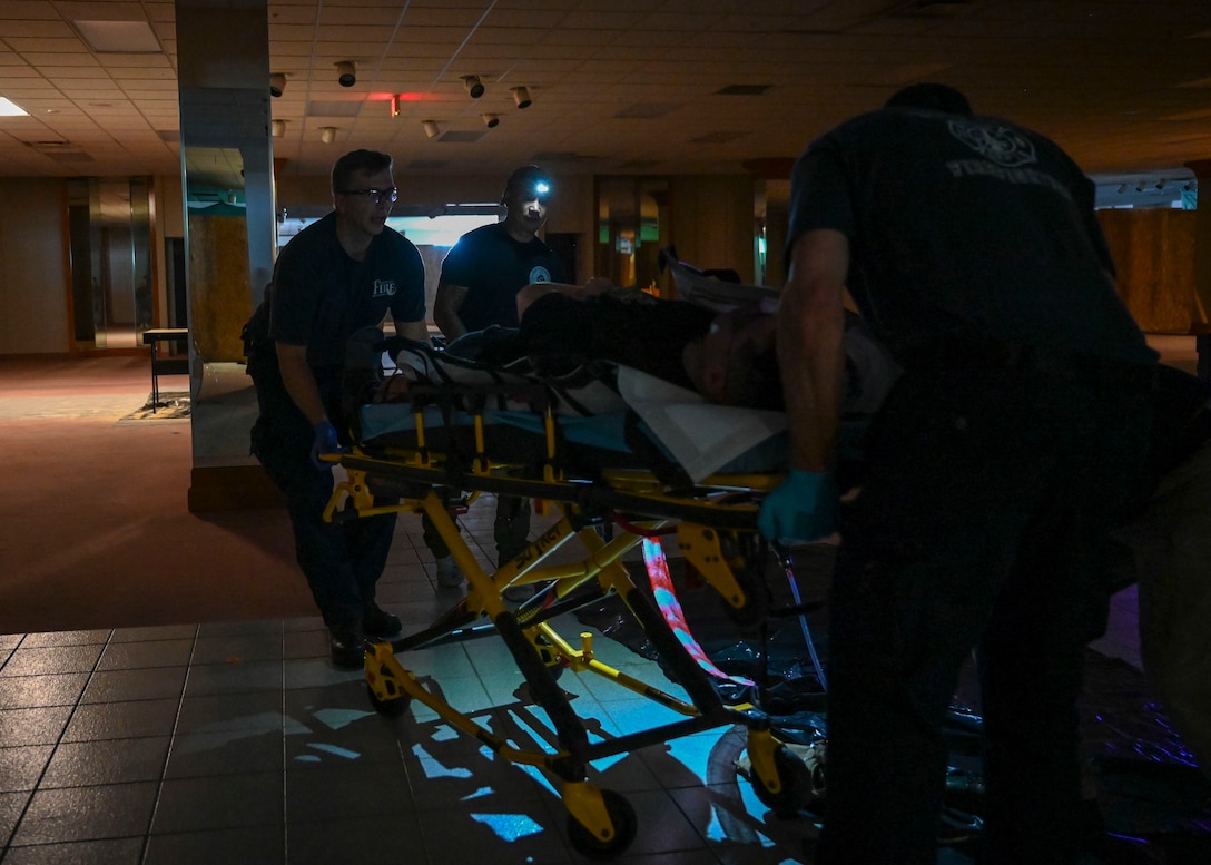 Two paramedics push a patient on a gurney.