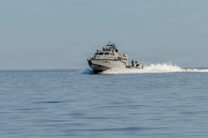 People sail in a military ship across a lake.