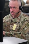 U.S. Soldier wearing a headset while working on a computer.