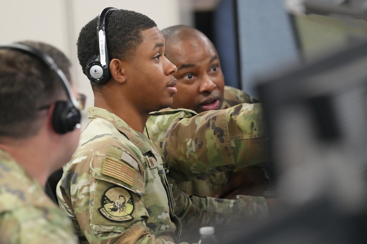 U.S. Airmen wearing headsets while working on computers: