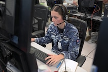 Royal Australian Air Force warfighter wearing a headset works on a computer