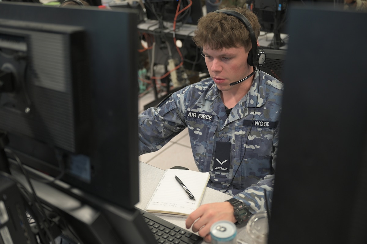 Royal Australian Air Force warfighter wearing a headset works on a computer