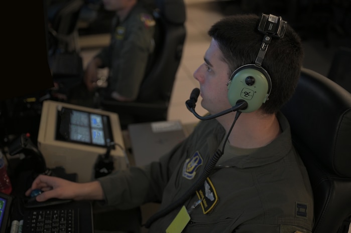uniformed USAF Airmen fly MQ-9 simulators