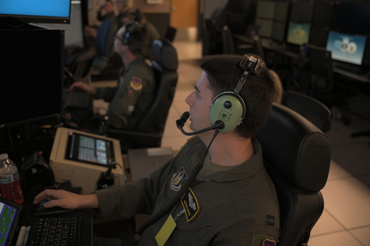 uniformed USAF Airmen fly MQ-9 simulators
