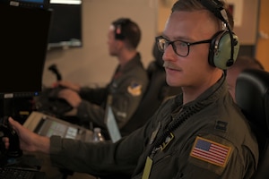 uniformed USAF Airmen fly MQ-9 simulators