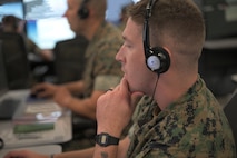 U.S. Marines wearing headsets work on computers