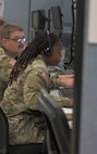 U.S. Air Force warfighters wearing headsets work on computers