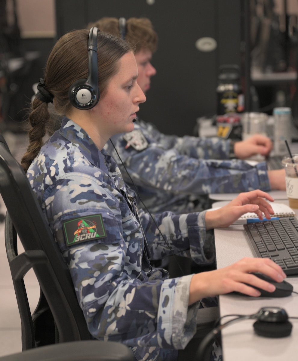Royal Australian Air Force warfighters wearing headsets work on computers