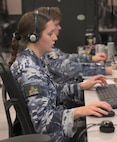 Royal Australian Air Force warfighters wearing headsets work on computers