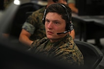 U.S. Marines wearing headsets work on computers