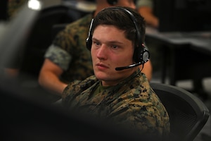 U.S. Marines wearing headsets work on computers