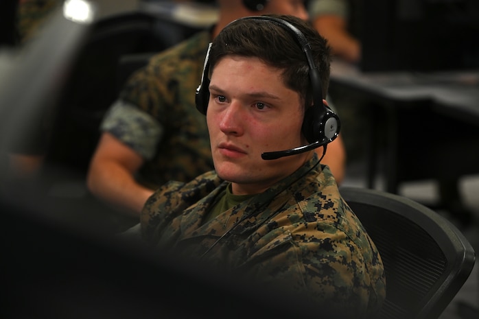 U.S. Marines wearing headsets work on computers