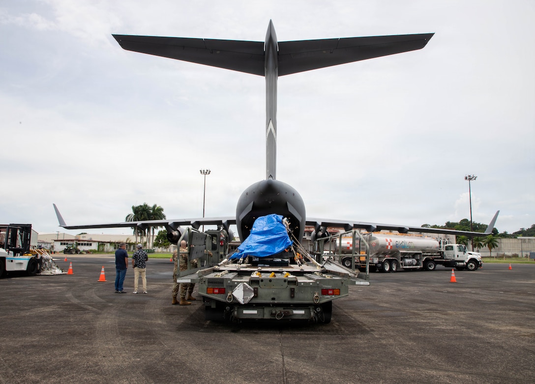 U.S. service members and Panamanians prepare to load machinery into a C-17 Globemaster III