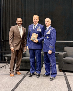an airman in the middle holds a plaque