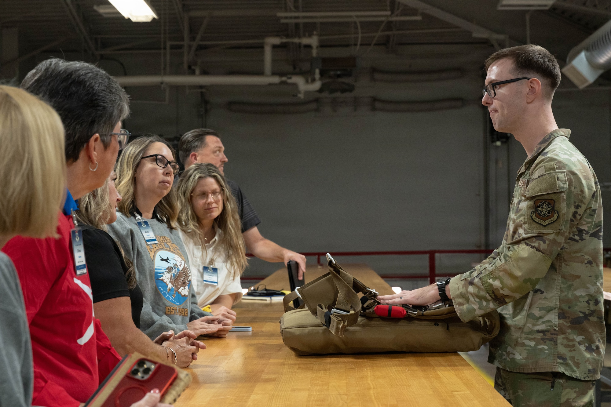 U.S. Air Force Staff Sgt. Benjamin Meadows, 317th Operations Support Squadron aircrew flight equipment craftsman, demonstrates a parachute system to Air Mobility Command civic leaders at Dyess Air Force Base, Texas, Aug. 25, 2026. Aircrew flight equipment specialists inspect, maintain and prepare lifesaving equipment to help ensure aircrew readiness and safety. (U.S. Air Force photo by Airman 1st Class Layla Desch)