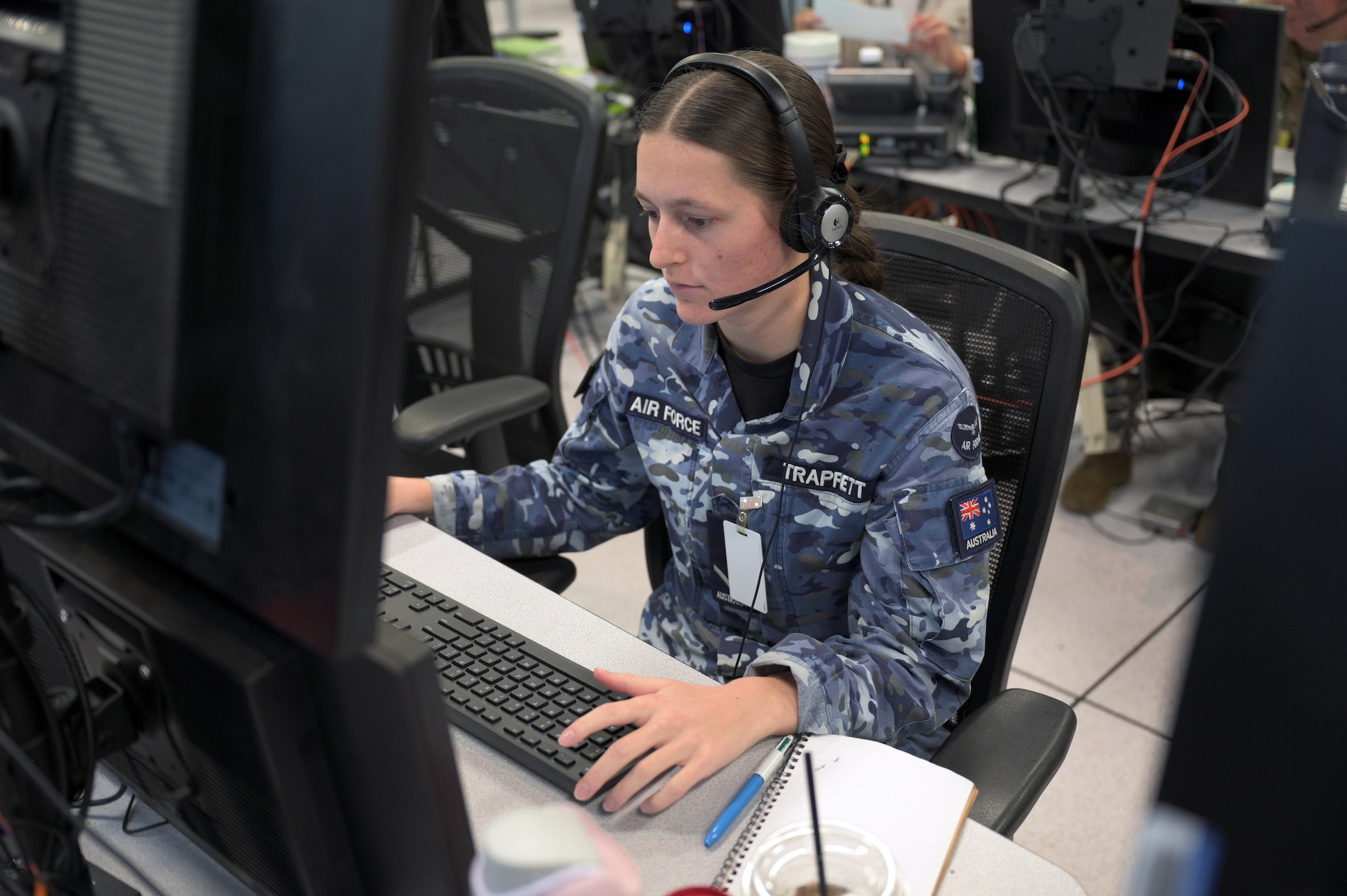 Royal Australian Air Force warfighter wearing a headset works on a computer