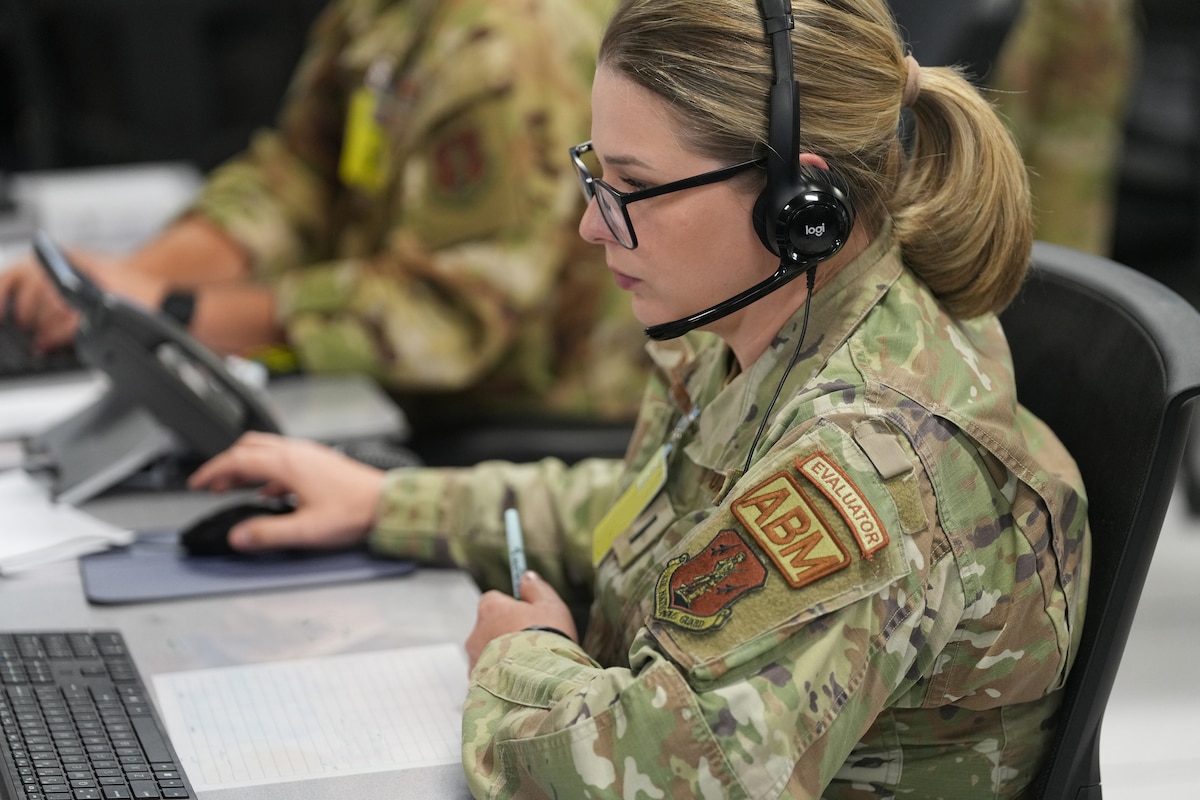 U.S. Airmen wearing headsets while working on computers