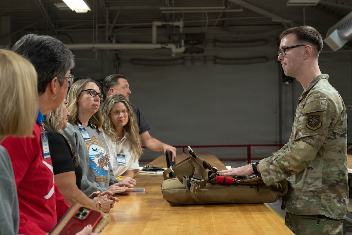 U.S. Air Force Staff Sgt. Benjamin Meadows, 317th Operations Support Squadron aircrew flight equipment craftsman, demonstrates a parachute system to Air Mobility Command civic leaders at Dyess Air Force Base, Texas, Aug. 25, 2026. Aircrew flight equipment specialists inspect, maintain and prepare lifesaving equipment to help ensure aircrew readiness and safety. (U.S. Air Force photo by Airman 1st Class Layla Desch)