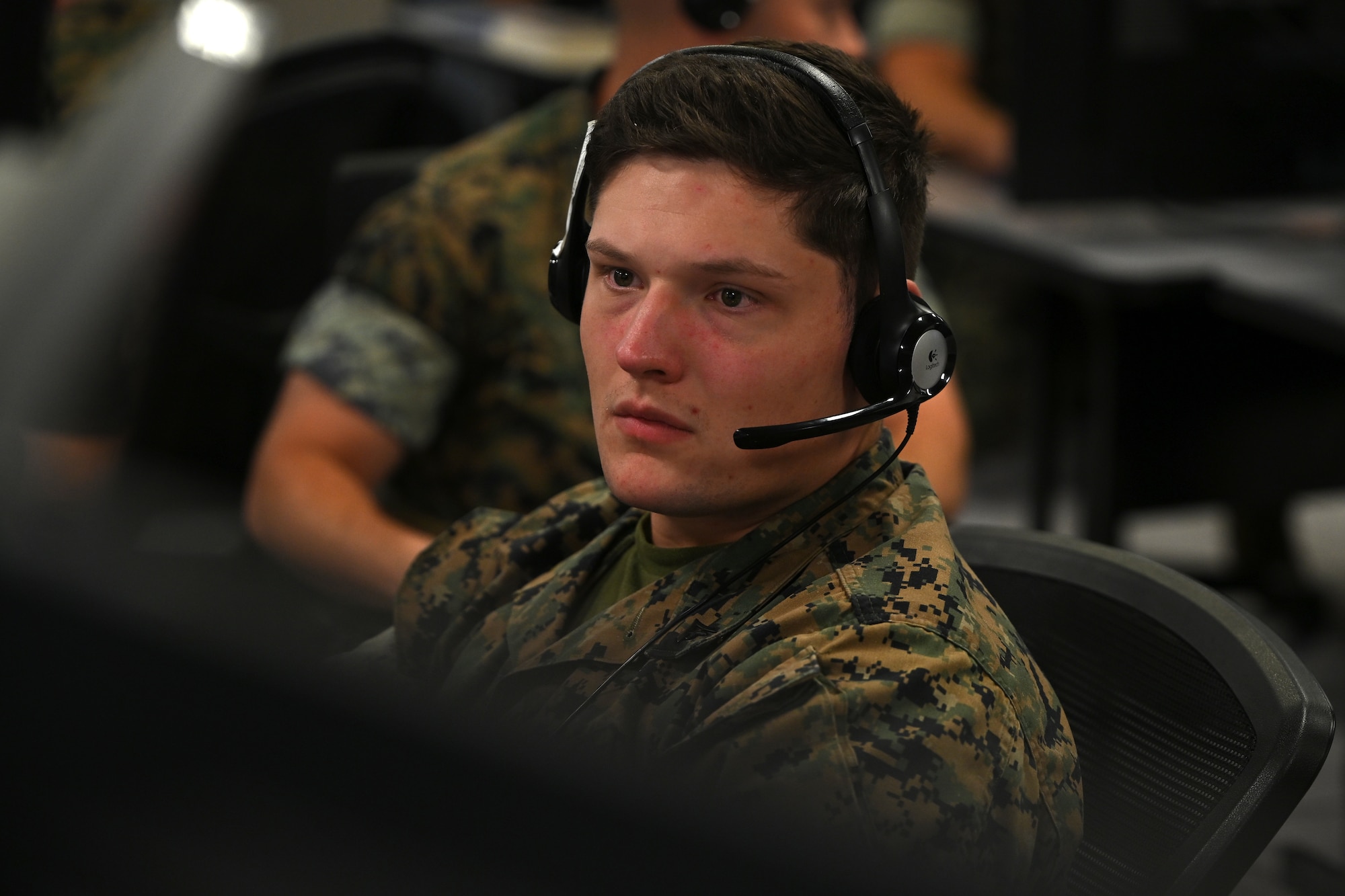 U.S. Marines wearing headsets work on computers