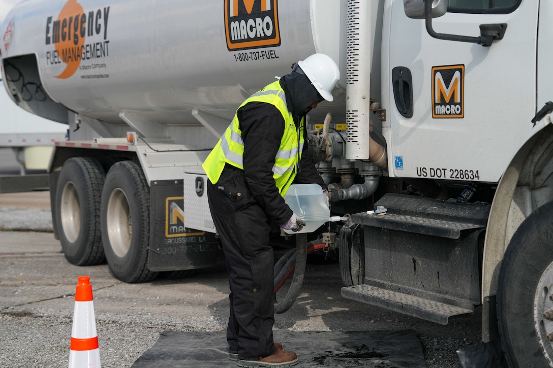 a man puts stands next to a fuel truck.