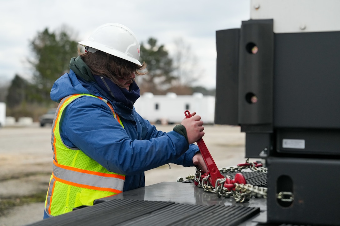 A man tightens tie down chains.