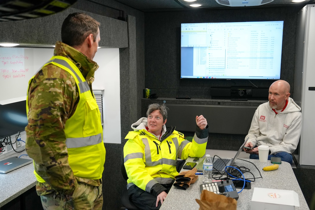 Individuals talk around a small table inside a tactical operations vehicle.