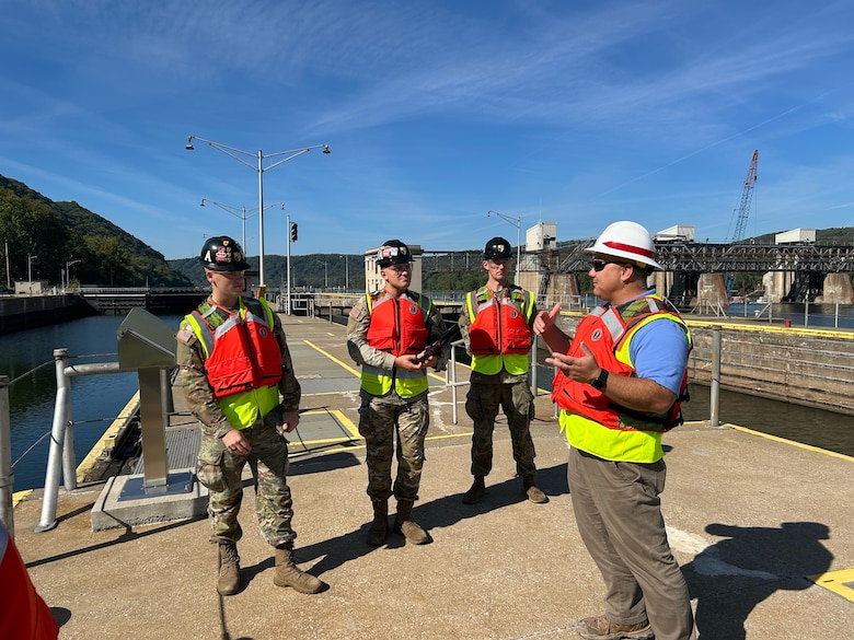 Three Soldiers talk with a man as they stand next to a waterways lock.