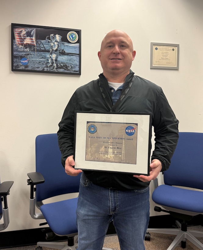 Man poses for a photo holding a certificate