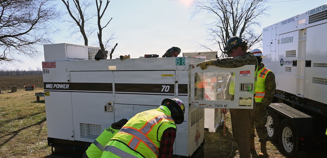 three men are seen working on a generator