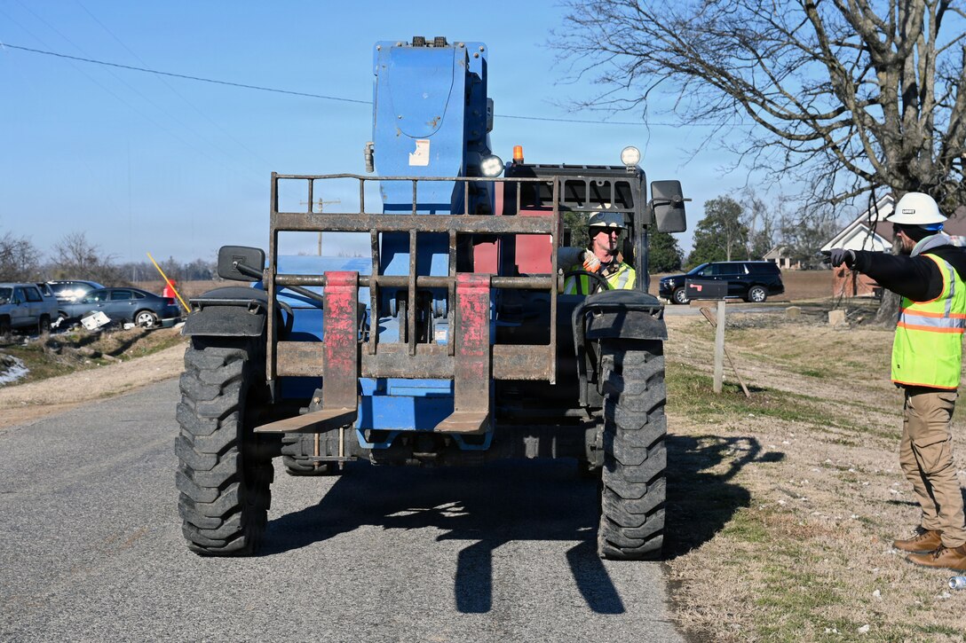 a man directs another man who is driving a forklift on where to go.