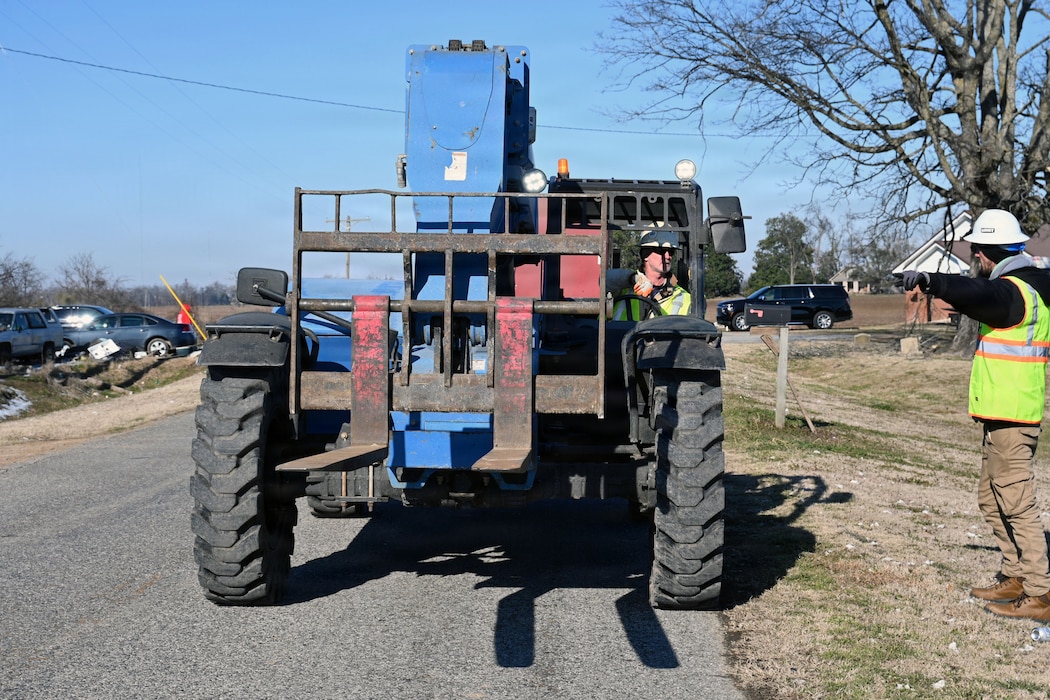 a man directs another man who is driving a forklift on where to go.