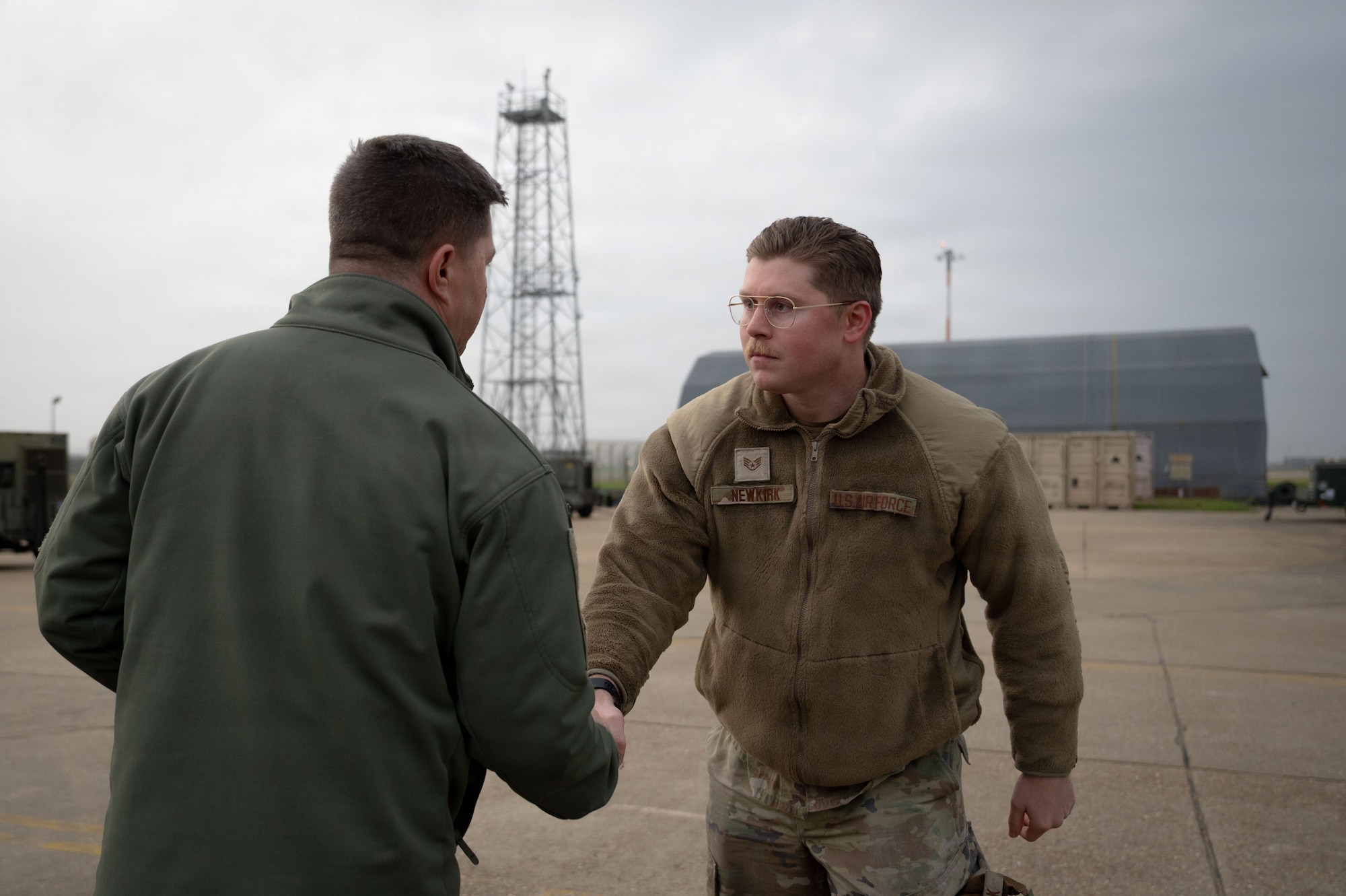 U.S. Air Force Staff Sgt. Austin Newkirk, right, 100th Civil Engineer Squadron liquid fuels technician, shakes hands with Col. Steven Byrum, 100th Air Refueling Wing commander, as he is awarded a challenge coin on RAF Mildenhall, England, Jan. 26, 2026.