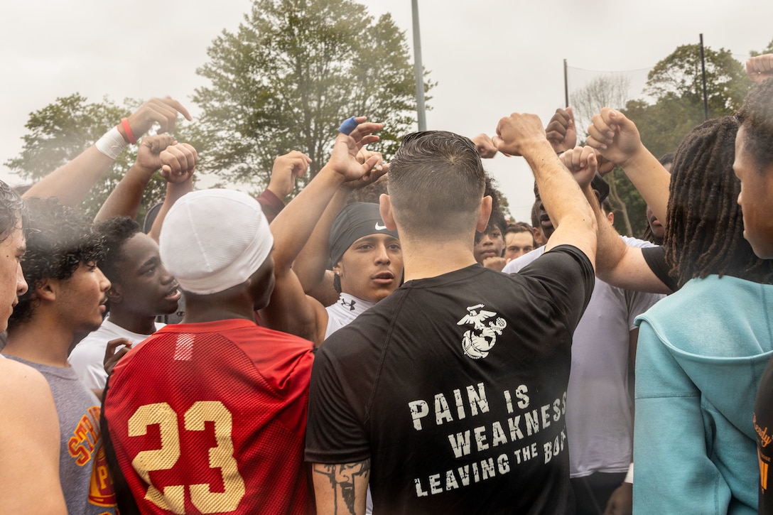 Students with Stratford High School, perform a pregame ritual after conducting the combat fitness test (CFT) at Penders Field in Stratford, Connecticut, Aug. 20, 2025. The CFT assesses a Marine’s ability to perform high-intensity combat-related tasks and consists of three events: movement to contact, ammunition can lift, and the maneuver under fire. (U.S. Marine Corps photo by Sgt. Hernan Rodriguez)