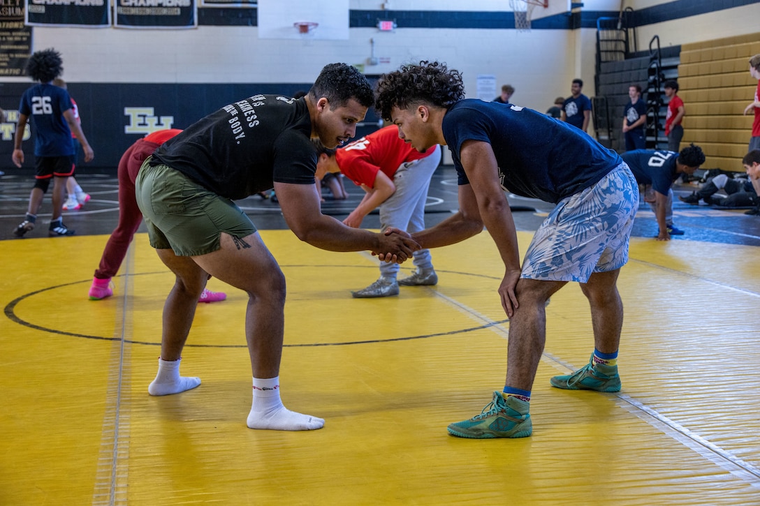 U.S. Marine Staff  Sgt. Jason Gordan, a recruiter with Recruiting Station Springfield, prepares to wrestle a high school student during a wrestling clinic with the United States Marines Corps Sports Leadership Academy (USMC SLA) at East Hartford High School, Hartford Connecticut, Oct. 19, 2024. The USMC SLA is an organization designed to teach athletes the fundamentals of Marine Corps leadership techniques and skills through sports to help them in their high school sports careers. (U.S. Marine Corps photo by Sgt. Hernan Rodriguez)