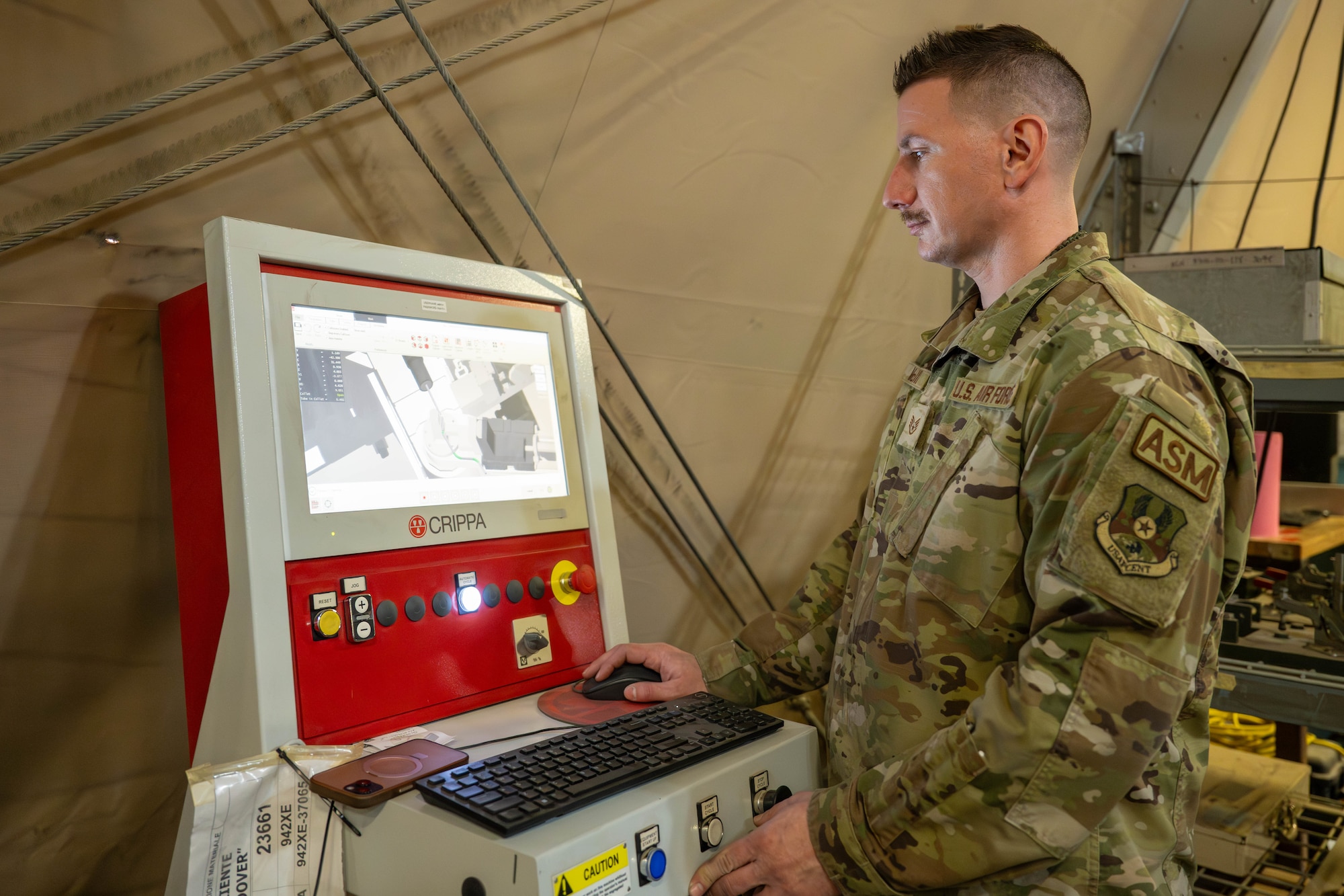 U.S. Air Force Staff Sgt. Matthew McKoin, 332nd Expeditionary Maintenance Squadron aircraft structural maintenance technician, enters data into a computer connected to a Crippa machine in the U.S. Central Command area of responsibility, Jan. 28, 2026. The system automates hydraulic tube fabrication for aircraft maintenance operations. (U.S. Air Force photo by Senior Airman Kari Degraffenreed)