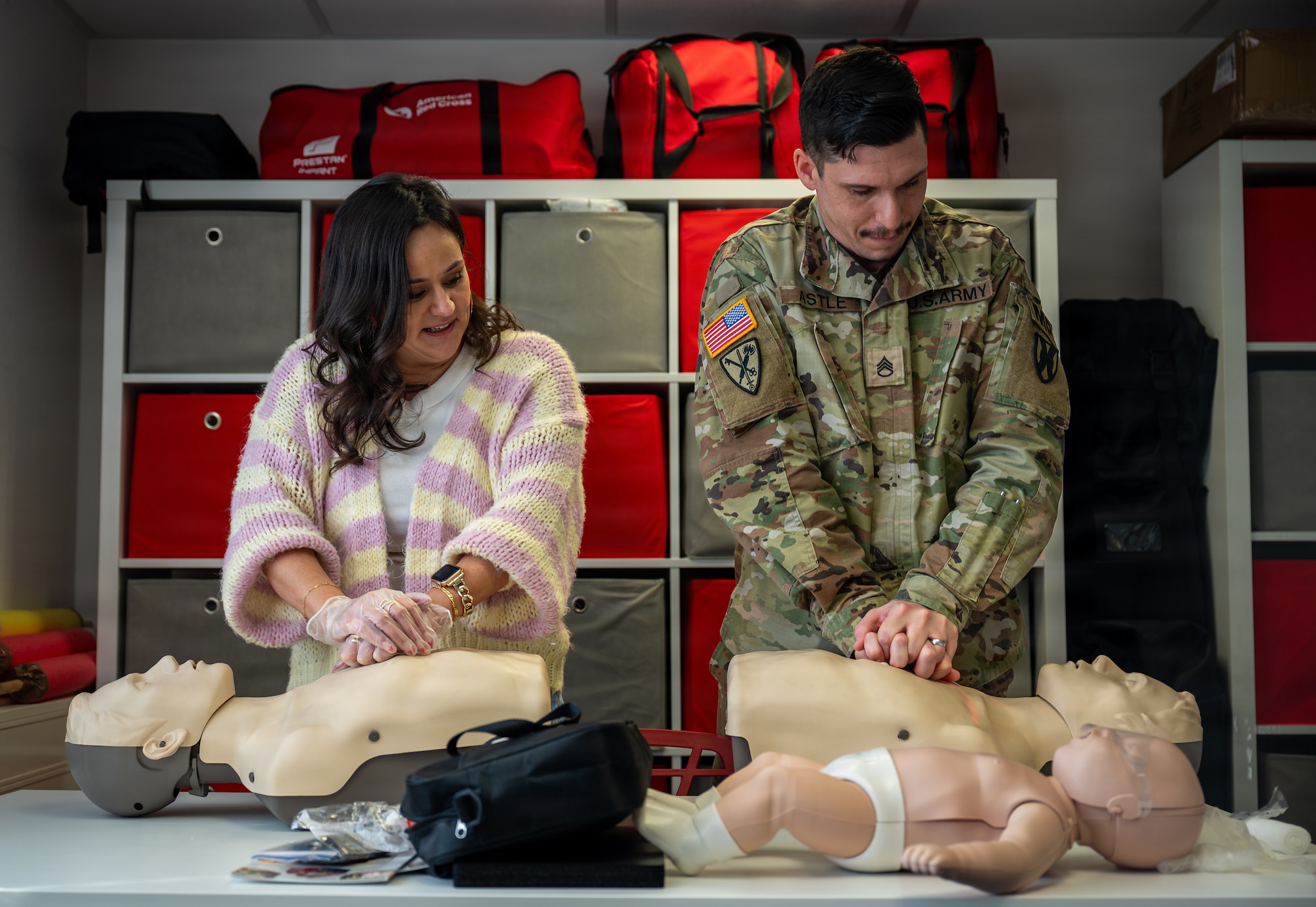U.S. Army Staff Sgt. Colin Astle, Rhine Ordnance Barracks directorate of emergency services desk sergeant, and his wife Jessica Astle, Kaiserslautern Elementary School teacher, perform chest compressions on a Braden BigRed life-saving mannequin during an American Red Cross Ramstein Office Adult and Pediatric First Aid/CPR/AED course at Ramstein Air Base, Germany, Jan. 22, 2026.