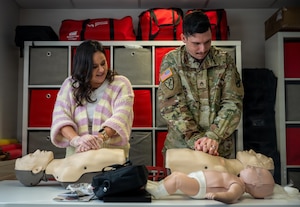 U.S. Army Staff Sgt. Colin Astle, Rhine Ordnance Barracks directorate of emergency services desk sergeant, and his wife Jessica Astle, Kaiserslautern Elementary School teacher, perform chest compressions on a Braden BigRed life-saving mannequin during an American Red Cross Ramstein Office Adult and Pediatric First Aid/CPR/AED course at Ramstein Air Base, Germany, Jan. 22, 2026.