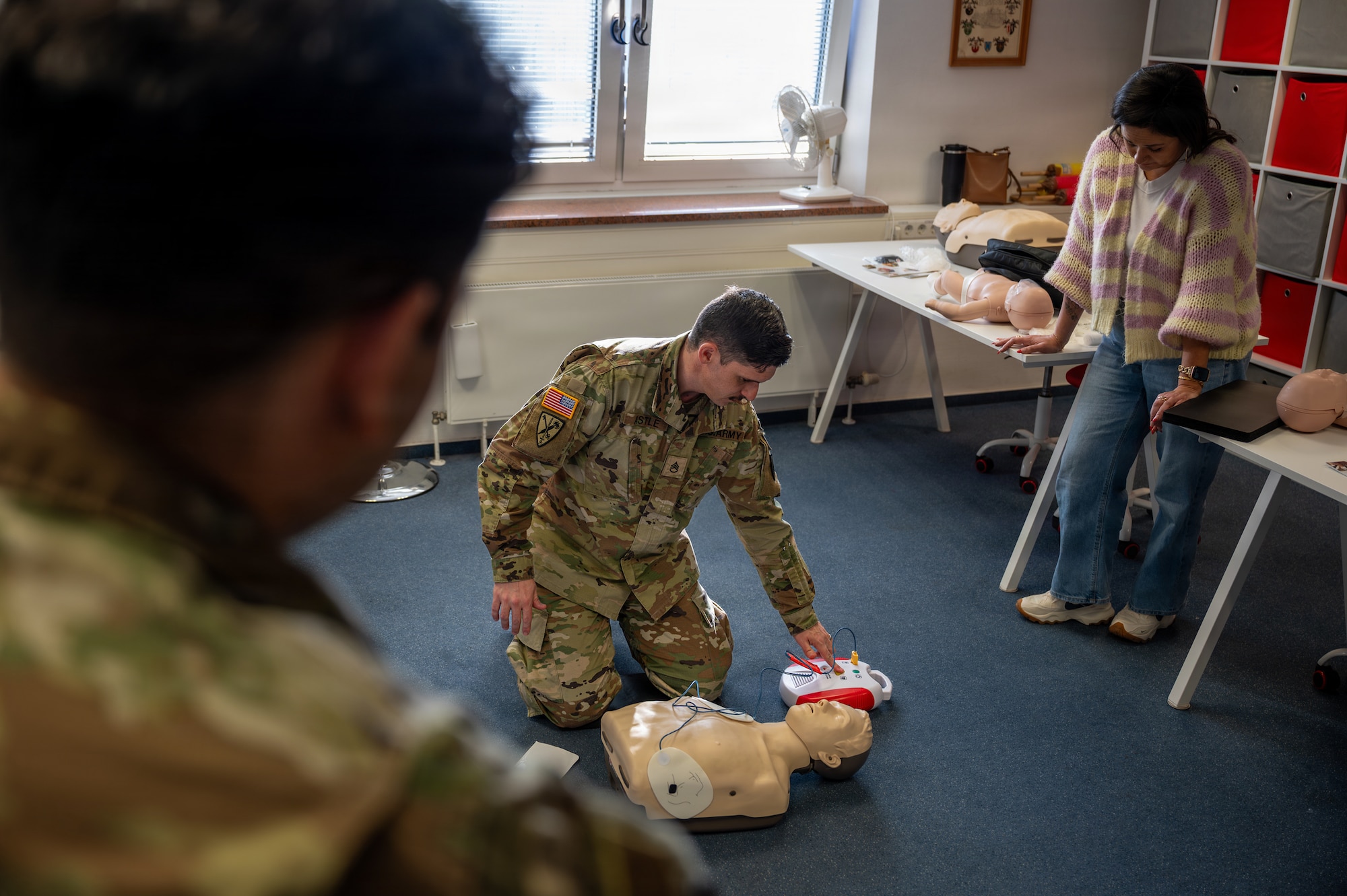 U.S. Army Staff Sgt. Colin Astle, Rhine Ordnance Barracks directorate of emergency services desk sergeant, demonstrates how to use an automated external defibrillator during an American Red Cross Ramstein Office Adult and Pediatric First Aid/CPR/AED course at Ramstein Air Base, Germany, Jan. 22, 2026