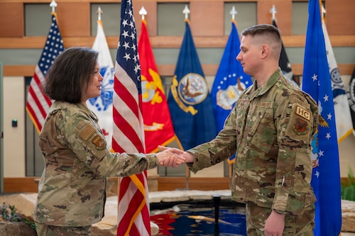 U.S. Air Force Col. Martha Sasnett, Air Force Mortuary Affairs Operations commander awards a coin to 2nd Lt. Christopher Browning, a reserve chaplain candidate, Dover Air Force Base, Delaware,  Jan. 29, 2026. After a short tour at AFMAO, 2nd Lt. Browning is now going through the process of finalizing documentation and working with a recruiter to find a gaining base until finally recommissioning as a fully qualified Air Force Chaplain. (U.S. Air Force photo by Staff Sgt. Frank Rohrig)