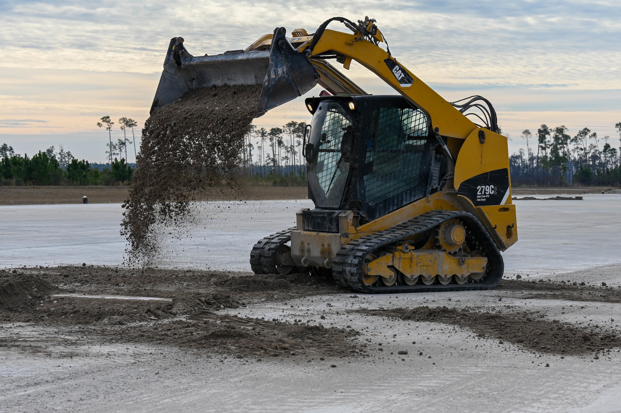A track loader dumps dirt.