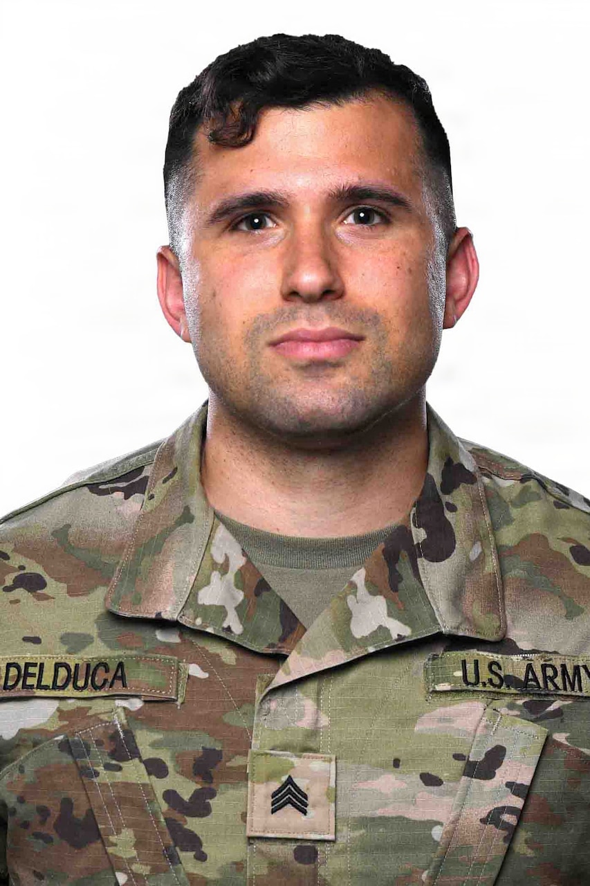 A man wearing a camouflage military uniform poses for a photo.