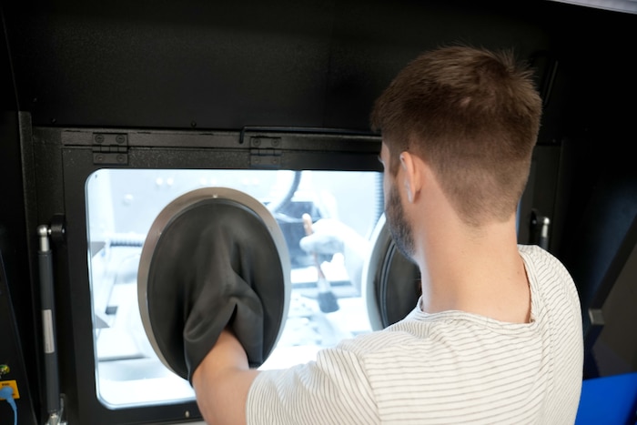 man brushing metal shavings into sifter