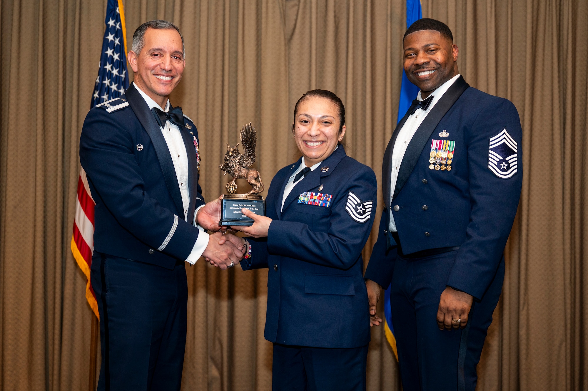 Col. Alfred Rosales, 319th Reconnaissance Wing commander, left and Chief Master Sgt. Marcus Cook Perry, 319th MSG command chief, right, present SrA Emily Wagner, Wing Staff Agency, the Ceremonial Guardsman of the year, during the 319th Reconnaissance Wing’s 2025 annual awards ceremony at Grand Forks Air Force Base, North Dakota, Jan. 29, 2026