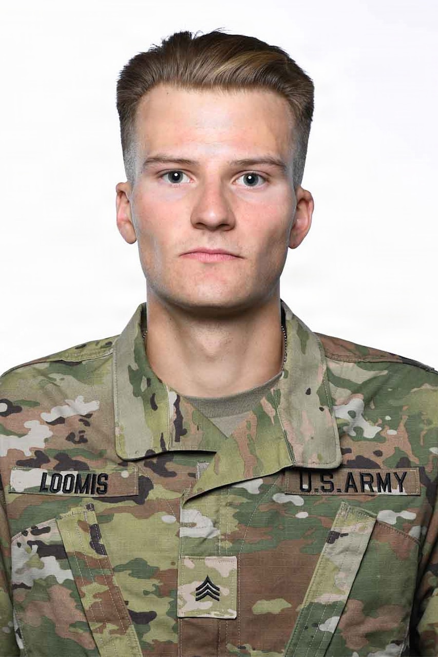 A man wearing a camouflage military uniform poses for a photo.