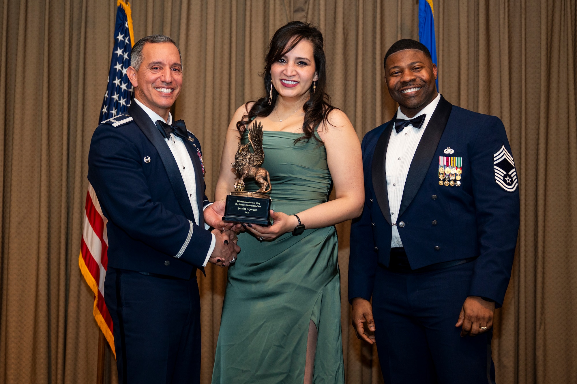 Col. Alfred Rosales, 319th Reconnaissance Wing commander, left and Chief Master Sgt. Marcus Cook Perry, 319th MSG command chief, right, present Jessica O. Jordan the Key Support Liaison of the year award during the 319th Reconnaissance Wing’s 2025 annual awards ceremony at Grand Forks Air Force Base, North Dakota, Jan. 29, 2026.
