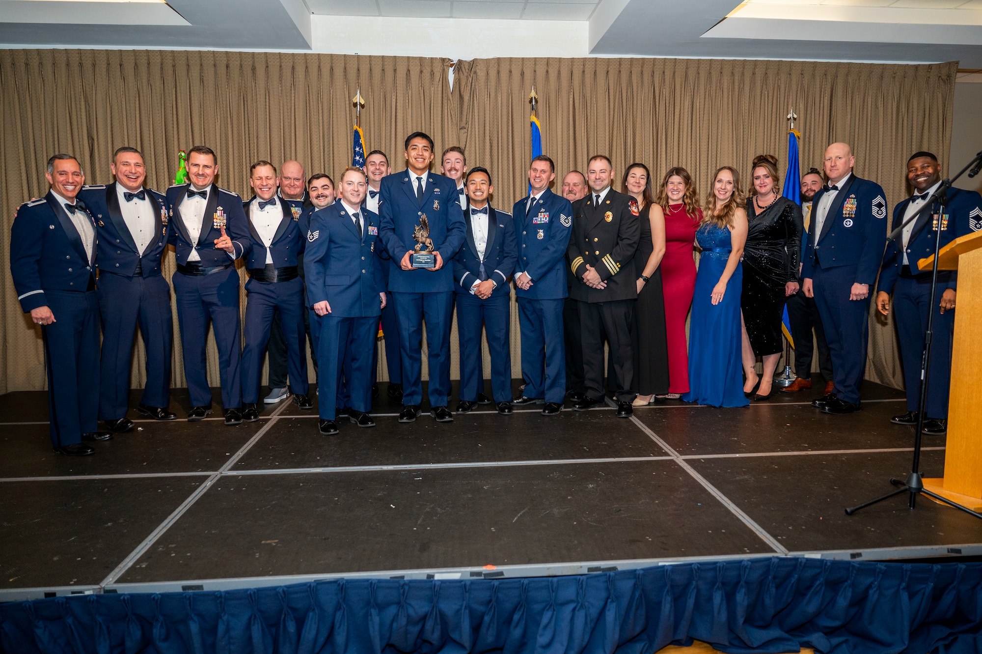 Col. Alfred Rosales, 319th Reconnaissance Wing commander, left and Chief Master Sgt. Marcus Cook Perry, 319th MSG command chief, right, present the 319th Civil Engineer Squadron with the Unit of the year award during the 319th Reconnaissance Wing’s 2025 annual awards ceremony at Grand Forks Air Force Base, North Dakota, Jan. 29, 2026.