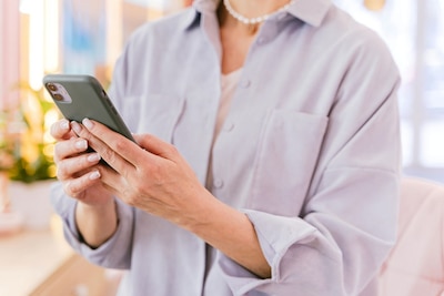 Woman in a lavender shirt looking at her cellphone.