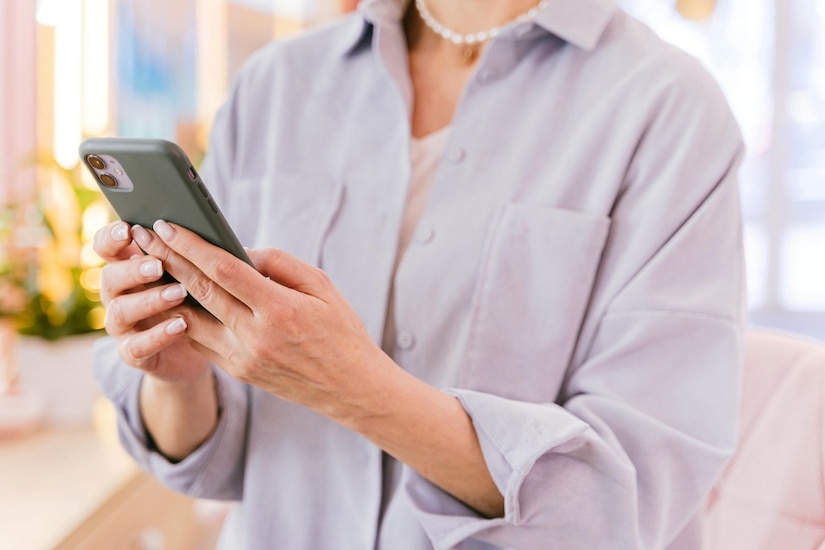 Woman in a lavender shirt looking at her cellphone.