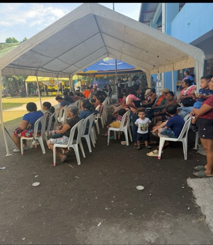 Patients sit under a tent