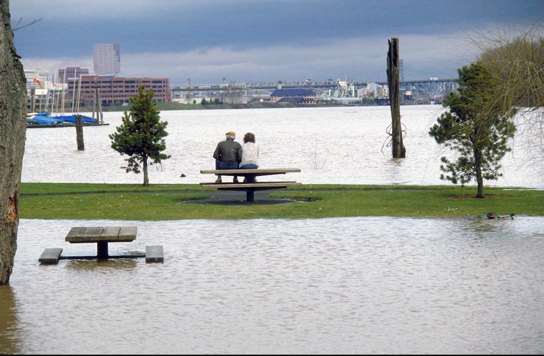A couple looks west across a flooded Willamette River in downtown Portland, Oregon on Feb. 8, 1996. The flooding was the result of an atmospheric river, and engineers and technicians at with the U.S. Army Corps of Engineers worked around the clock to manipulate more than 60 dams in the Columbia River system to minimize flooding. (U.S. Army photo/Billie Johnson)